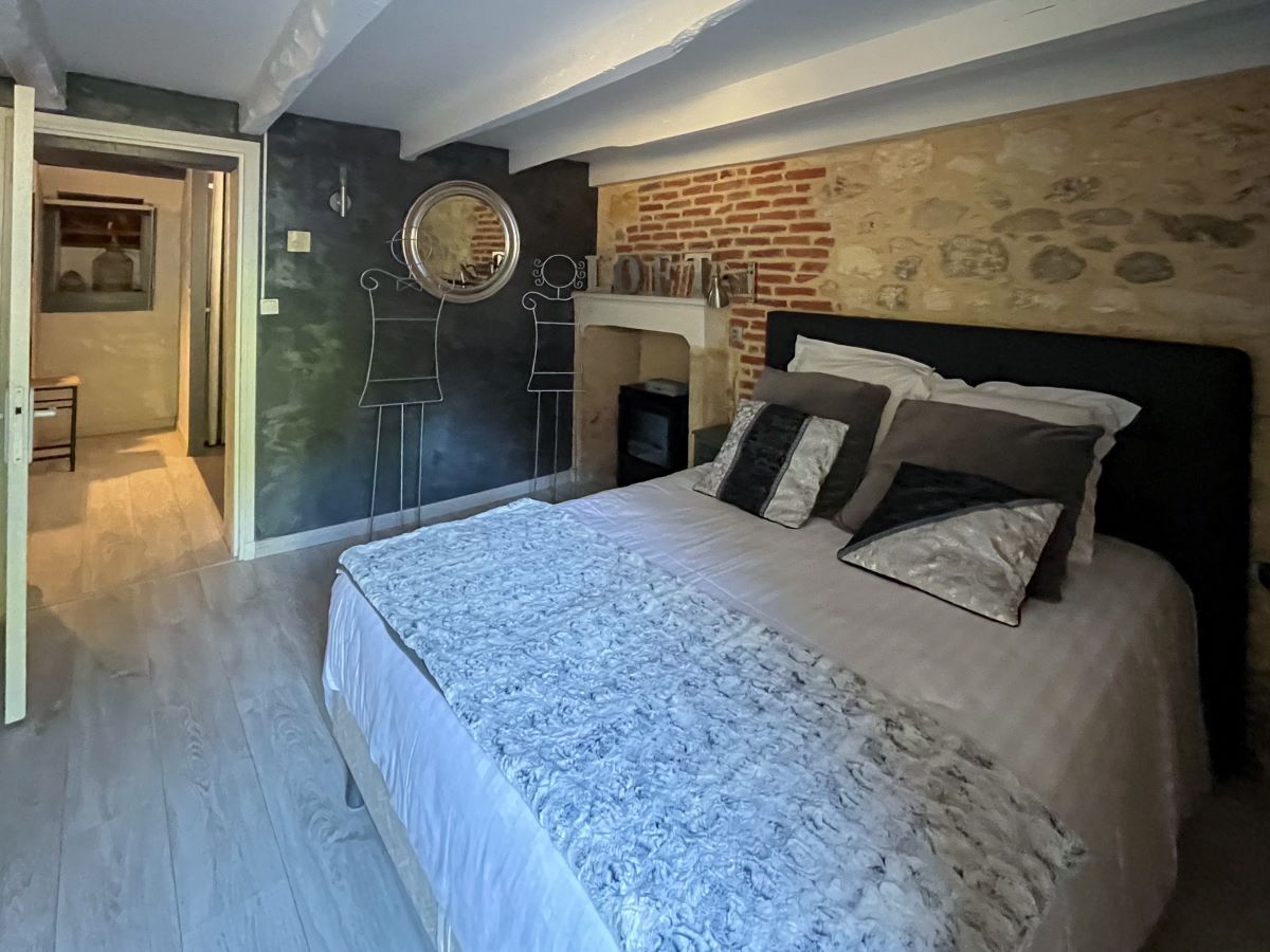 Pont en pierre, terrasse de restaurant provençale Petit pont de pierre sèche et moellons au-dessus d'un canal d'eau, menant à une terrasse de restaurant avec tables sous une structure en bois à toiture de tuiles.